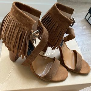 Beige suede open toe shoes with fringe.